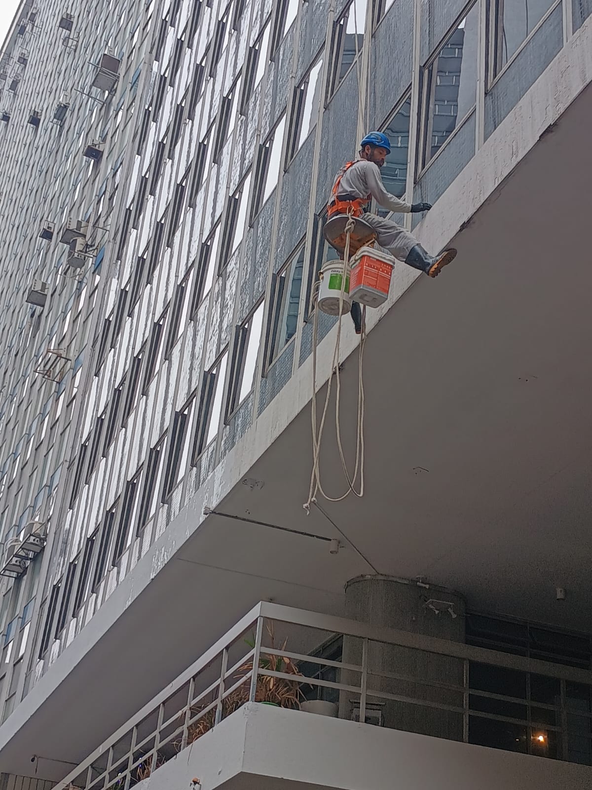 Profissional da RG Serviços em Fachadas realizando limpeza de fachada predial com acesso por corda