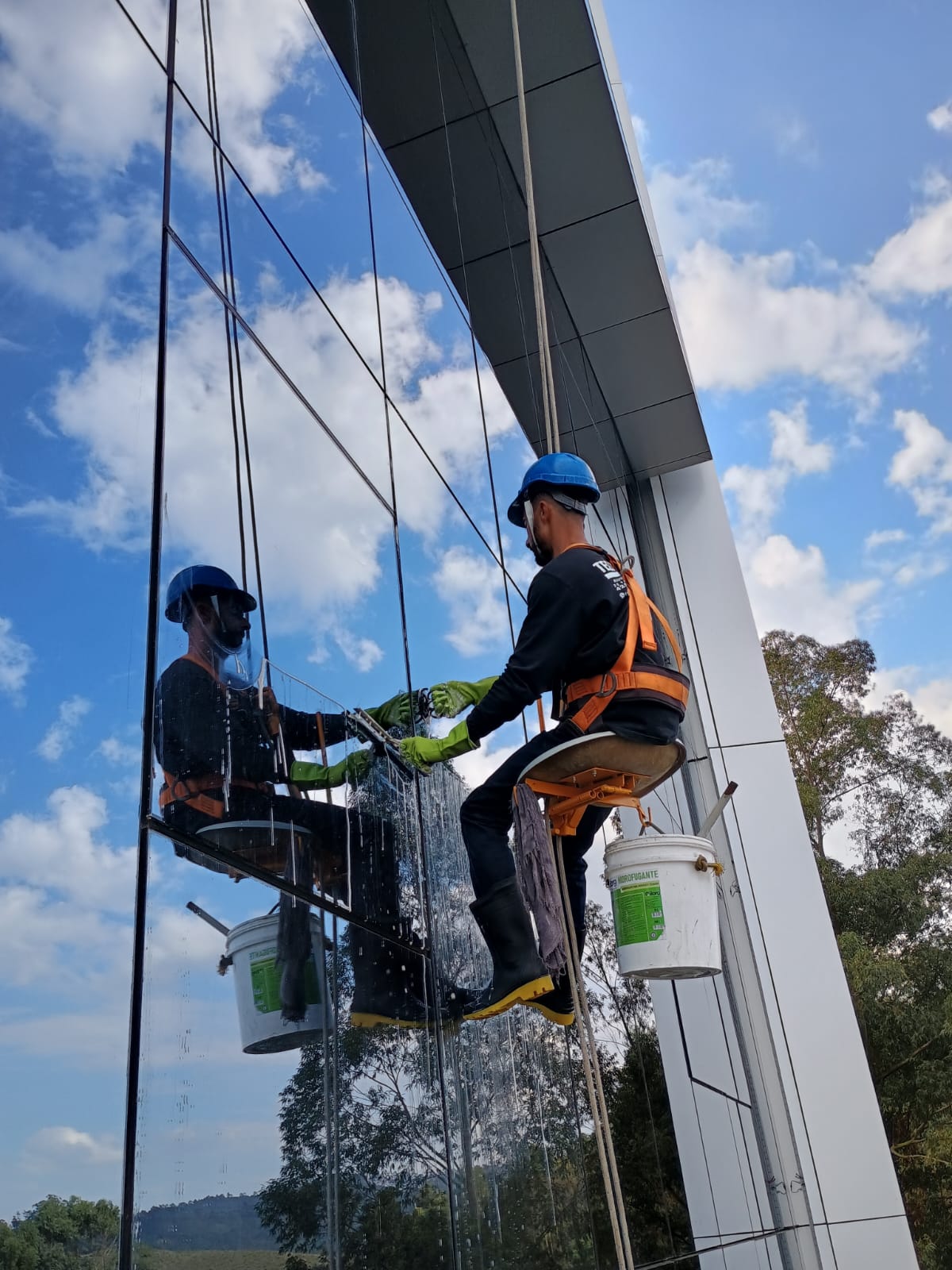 Limpeza de vidros em altura com técnica de acesso por corda e equipamentos de segurança